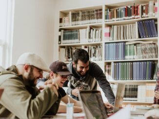 trois hommes consultent les chronques web entreprise en regardant l'ordinateur portable à l'intérieur de la pièce